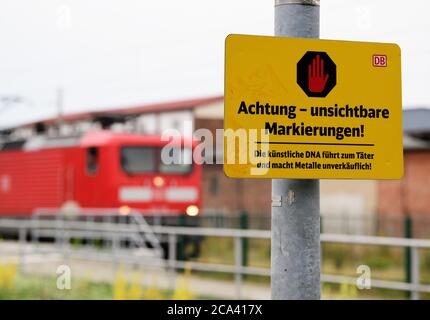 02. August 2020, Brandenburg, Golßen: Ein Schild mit der Aufschrift 'Achtung - unsichtbare Markierungen! Die künstliche DNA führt zum Täter und macht Metalle unverkäuflich" steht in der Nähe der Station neben den Gleisen. Foto: Soeren Sache/dpa-Zentralbild/dpa Stockfoto