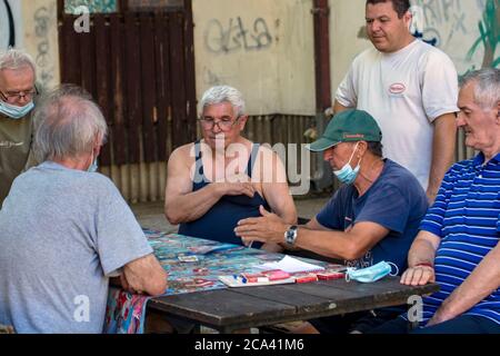 Zrenjanin, Serbien, 29. Juli 2020. Ältere Herren und Rentner spielen jeden Tag Karten im Schatten eines großen Baumes. Es gibt immer neugierige Beobachter Stockfoto