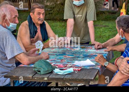 Zrenjanin, Serbien, 29. Juli 2020. Ältere Herren und Rentner spielen jeden Tag Karten im Schatten eines großen Baumes. Es gibt immer neugierige Beobachter Stockfoto