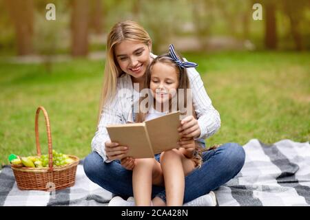 Mutter Und Tochter Lesebuch Sitzen Auf Plaid In Der Landschaft Stockfoto