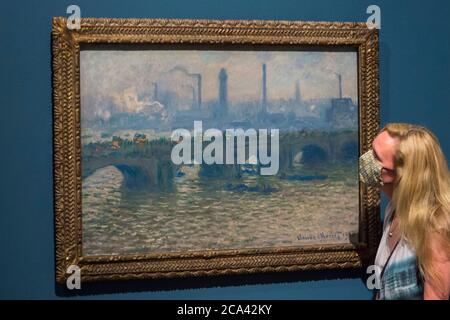 London, Großbritannien. August 2020. Ein Mitarbeiter posiert mit 'Waterloo Bridge, Overcast', 1903, von Claude Monet. Vorschau auf 'Gauguin und die Impressionisten : Meisterwerke aus der Ordrupgaard Collection' an der Royal Academy of Arts in Piccadilly. 60 Werke aus einer Sammlung impressionistischer Gemälde des wohlhabenden dänischen Ehepaars Wilhelm und Henny Hansen, die vom 7. August bis zum 18. Oktober 2020 ausgestellt werden, sind Meisterwerke von Gauguin, Degas, Monet, Morisot, Pissarro, Renoir und Sisley. Kredit: Stephen Chung / Alamy Live Nachrichten Stockfoto