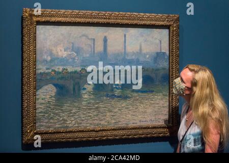 London, Großbritannien. August 2020. Ein Mitarbeiter posiert mit 'Waterloo Bridge, Overcast', 1903, von Claude Monet. Vorschau auf 'Gauguin und die Impressionisten : Meisterwerke aus der Ordrupgaard Collection' an der Royal Academy of Arts in Piccadilly. 60 Werke aus einer Sammlung impressionistischer Gemälde des wohlhabenden dänischen Ehepaars Wilhelm und Henny Hansen, die vom 7. August bis zum 18. Oktober 2020 ausgestellt werden, sind Meisterwerke von Gauguin, Degas, Monet, Morisot, Pissarro, Renoir und Sisley. Kredit: Stephen Chung / Alamy Live Nachrichten Stockfoto