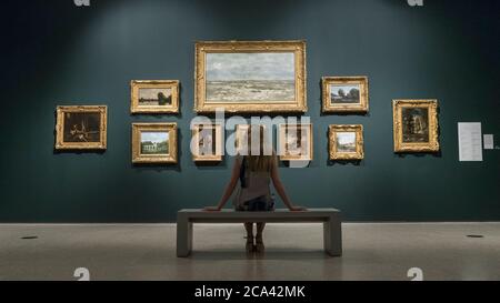 London, Großbritannien. August 2020. Ein Mitarbeiter posiert mit Werken von Delacroix und Corot in einer Nachbildung einer Ausstellung in Ordrupgaard. Vorschau auf 'Gauguin und die Impressionisten : Meisterwerke aus der Ordrupgaard Collection' an der Royal Academy of Arts in Piccadilly. 60 Werke aus einer Sammlung impressionistischer Gemälde des wohlhabenden dänischen Ehepaars Wilhelm und Henny Hansen, die vom 7. August bis zum 18. Oktober 2020 ausgestellt werden, sind Meisterwerke von Gauguin, Degas, Monet, Morisot, Pissarro, Renoir und Sisley. Kredit: Stephen Chung / Alamy Live Nachrichten Stockfoto