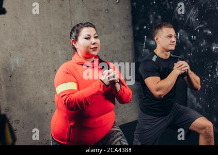 Plump Frau arbeitet mit aporty fit Mann. Fitness, sportliche Aktivität, Gewichtsverlust Konzept. Seitenansicht Nahaufnahme Stockfoto