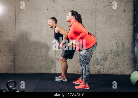 Volle Länge Seitenansicht Foto. Plump Frau mit Personal Trainer. Trainingsprogramm hilft Ihnen, Muskeln zu gewinnen und Fett zu verlieren Stockfoto