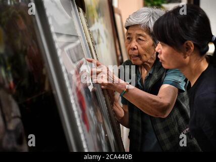 (200804) -- ZHENGZHOU, 4. August 2020 (Xinhua) -- Wang Suhua stellt Stiche bei einer Stickarbeit in ihrer Firma in Kaifeng, Provinz Henan in Zentralchina, vor, 30. Juli 2020. Wang Suhua, 85, ein immaterielles Kulturerbe auf nationaler Ebene, der die bianische Stickerei erbt, macht die Arbeit seit 1957. Durch das Sammeln alter bischer Stickarbeiten und das Aussortieren traditioneller Stickkunst in der Song Dynastie schufen Wang und ihre Arbeitskollegen mehr als zehn neue Sticharten und machten erfolgreich ein bisches Stickmeisterwerk des berühmten alten Gemäldes "entlang des Flusses während der Qingmin Stockfoto