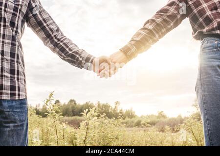 Liebe - romantisches Paar, das Hände hält, Sonnenuntergang. Liebhaber oder frisch verheiratete junge Paar gehen im Feld, schönen Sonnenuntergang. Stockfoto