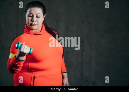 Plump Frau entwickeln ihre Muskeln mit Hantel. Nahaufnahme Foto. Hobby, Lifestyle, fit halten. Copy space Stockfoto