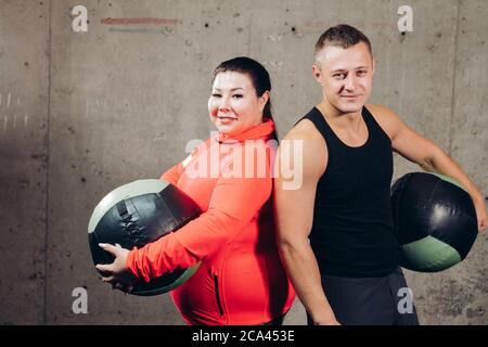 Glücklich übergewichtige Frau und schlanken Mann hält Übung Bälle, Nahaufnahme Porträt. studion Schuss. Fitness, Gesundheit Stockfoto