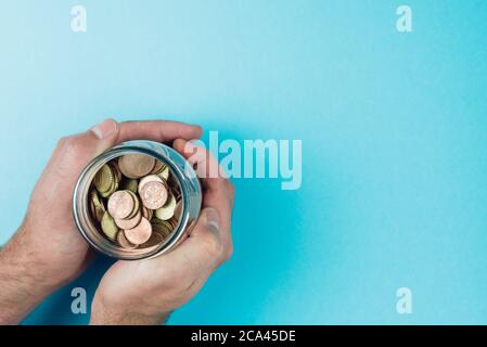 Oben Ansicht der Hände halten Glas mit kleinen Wechsel, Einsparungen und Investitionskonzept gefüllt Stockfoto