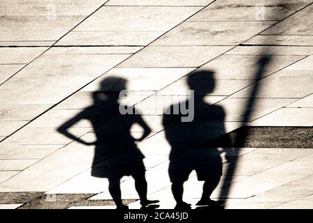 Verschwommene Schatten Silhouette von zwei jungen Menschen zu Fuß oder warten, ein Mädchen mit Händen auf Hüften Stockfoto