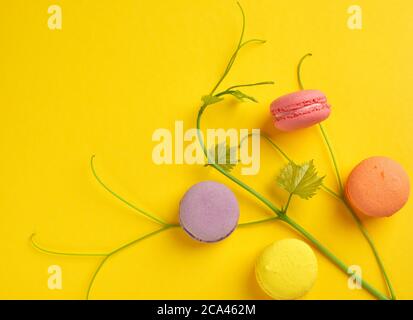 Runde mehrfarbige gebackene Macarons, Dessert liegt auf gelbem Hintergrund, Draufsicht Stockfoto