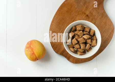 Knusprige Müsli- und Schokoladenkissen mit Milch. Brakefast mit Schokoladenkissen und Pfirsich auf weißem und Holzhintergrund. Stockfoto