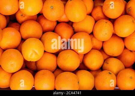 Orange Früchte - Haufen von Orangenfrüchten. Leuchtend orange Orangen in einer Box Nahaufnahme. Stockfoto