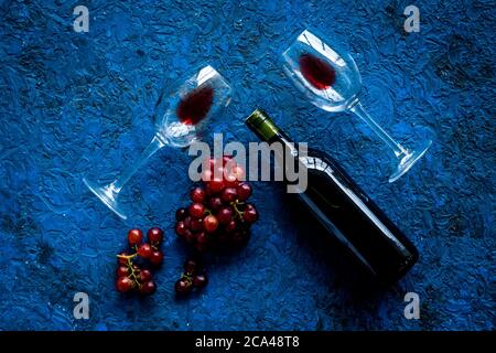 Rotwein mit Traube - in Gläsern und Flasche - auf blauem Schreibtisch von oben Stockfoto