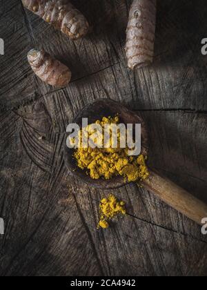 Kurkuma (Curcumin, Curcuma Longa Linn), Pulver und Rhizom auf Holzpfanne und Vintage-Holztisch. Overhead-Aufnahme. Stockfoto