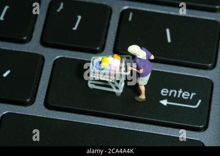 Eine Frau, die im Supermarkt sicher einkauft und eine Gesichtsmaske trägt. Miniatur Menschen Figuren Spielzeug konzeptionelle Fotografie. Stockfoto