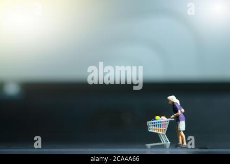 Eine Frau, die im Supermarkt sicher einkauft und eine Gesichtsmaske trägt. Miniatur Menschen Figuren Spielzeug konzeptionelle Fotografie. Stockfoto