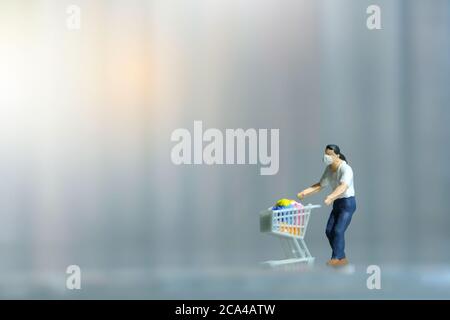 Ein Mann, der im Supermarkt sicher einkauft und eine Gesichtsmaske trägt. Miniatur Menschen Figuren Spielzeug konzeptionelle Fotografie. Stockfoto