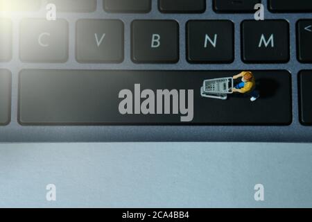 Eine Frau, die im Supermarkt sicher einkauft und eine Gesichtsmaske trägt. Miniatur Menschen Figuren Spielzeug konzeptionelle Fotografie. Stockfoto