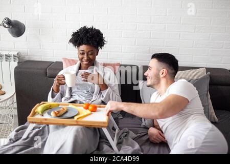 Multiethnisches Paar in Beziehung essen Frühstück im Bett Stockfoto