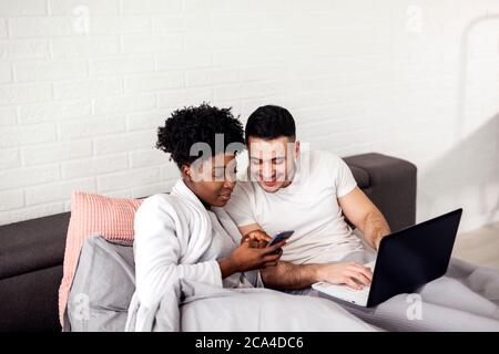Junges Paar, das im Bett im Internet surft Stockfoto
