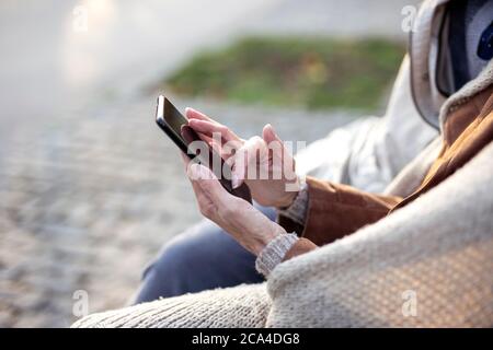 Konzentrieren Sie sich auf ältere Hände mit dem Mobiltelefon Stockfoto