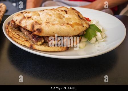 Cevapcici oder Cevapi, bosnische Gericht auf dem Grill zubereitet und mit Lepinja Brot serviert. Beliebtes Balkangericht. Stockfoto