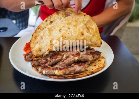 Cevapcici oder Cevapi, bosnische Gericht auf dem Grill zubereitet und mit Lepinja Brot serviert. Beliebtes Balkangericht. Stockfoto