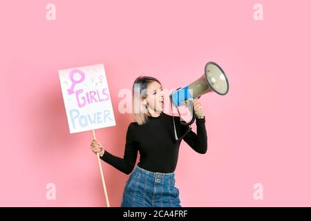 Portrait von jungen kaukasischen Mädchen hält Megaphon und Poster mit Inschrift MÄDCHEN MACHT, schreien und fördern Feminismus, tragen lässige Kleidung zu isolieren Stockfoto