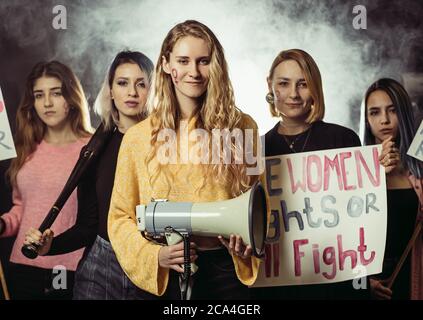Gruppe von lächelnden Mädchen feminsts Blick auf Kamera, mit Plakaten und Megaphon, kämpfen für Frauenrechte, tragen trendige Kleidung. Feminismus, feminine c Stockfoto