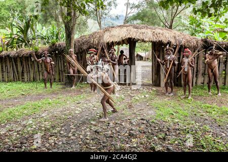 Wamena, Indonesien - 9. Januar 2010: Männer des Dani-Stammes in traditioneller Kleidung, die in der Nähe des Strohtors im Dorf Dugum Dani stehen. Baliem Valley Papua Stockfoto