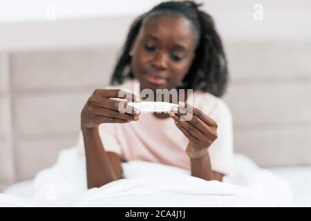 afro-Mädchen hält Thermometrter, verschwommener Hintergrund. Konzentrieren Sie sich auf die Hände mit Werkzeug. Stockfoto