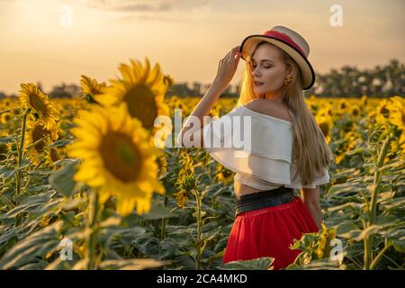 Portrait von jungen, glücklich blonde Haare Mädchen steht in einem Sonnenblumenfeld. Stockfoto