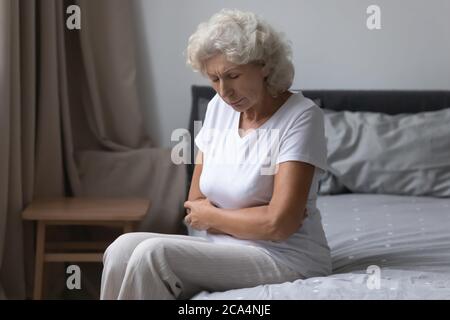 Ältere Frau aufgewacht leidet unter Bauchschmerzen Stockfoto