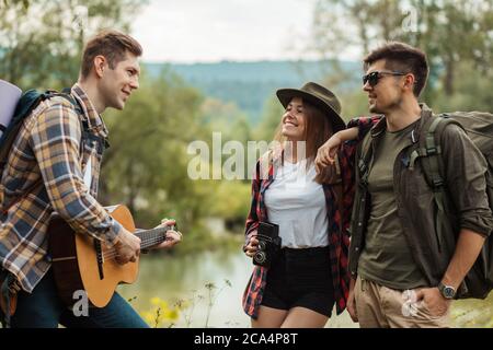 Junge fröhliche Paar genießen hören, ihre Freunde spielen die Gitarre, Glück, Freundschaft, Freizeit, Freizeit, Lebensstil Stockfoto