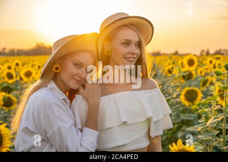 Porträt von jungen, glücklich blonde Haare Mädchen, Schwestern in einem Sonnenblumenfeld. Stockfoto