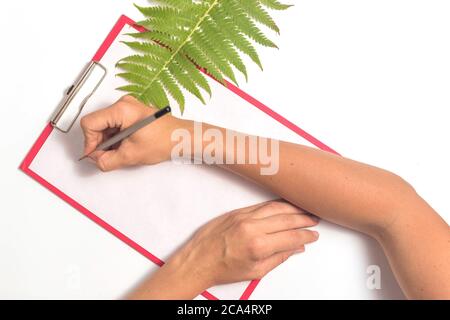 Weibliche Hände schreiben auf einem weißen Blatt Papier Stockfoto