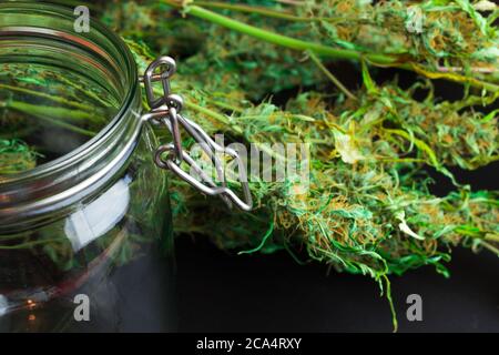 Öffnen Sie ein leeres Glas und eine Menge Cannabis Marihuana auf dem Hintergrund. Konzept der Unkrautbranche Stockfoto