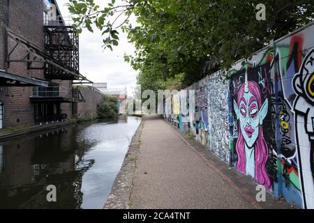 Szene mit Graffiti entlang des Grand Union Canal, ganz in der Nähe des Stadtzentrums am 3. August 2020 in Birmingham, Großbritannien. Birmingham hat rund 35 Meilen von Kanälen, angeblich mehr als in Venedig, und sind sehr viel eine Erinnerung an ein Birminghams Industrieerbe. Während der industriellen Revolution waren diese Kanäle beschäftigt, transportierten schwere Güter wie Kohle, Eisen, während sie eine entscheidende Rolle bei der Entwicklung von Birmingham als industrielles Kraftpaket spielten. Stockfoto