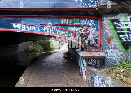 Szene mit Graffiti entlang des Grand Union Canal, ganz in der Nähe des Stadtzentrums am 3. August 2020 in Birmingham, Großbritannien. Birmingham hat rund 35 Meilen von Kanälen, angeblich mehr als in Venedig, und sind sehr viel eine Erinnerung an ein Birminghams Industrieerbe. Während der industriellen Revolution waren diese Kanäle beschäftigt, transportierten schwere Güter wie Kohle, Eisen, während sie eine entscheidende Rolle bei der Entwicklung von Birmingham als industrielles Kraftpaket spielten. Stockfoto