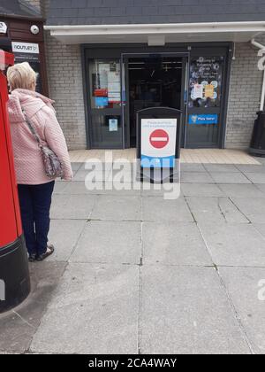 Schlange von Menschen außerhalb zeigen auf Höhe der Beschränkungen warten Zum Kauf von Waren und Einkaufen Covid 19 Coronavirus Soziale Distanzierung Stockfoto