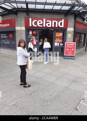 Schlange von Menschen außerhalb zeigen auf Höhe der Beschränkungen warten Zum Kauf von Waren und Einkaufen Covid 19 Coronavirus Soziale Distanzierung Stockfoto