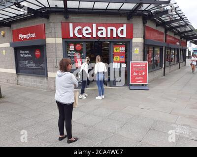 Schlange von Menschen außerhalb zeigen auf Höhe der Beschränkungen warten Zum Kauf von Waren und Einkaufen Covid 19 Coronavirus Soziale Distanzierung Stockfoto