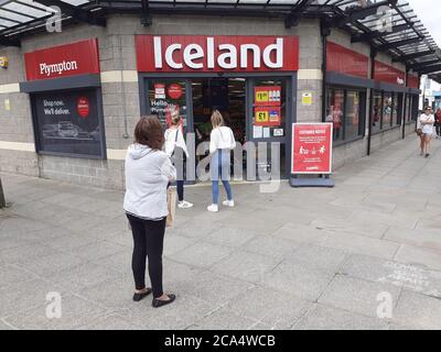 Schlange von Menschen außerhalb zeigen auf Höhe der Beschränkungen warten Zum Kauf von Waren und Einkaufen Covid 19 Coronavirus Soziale Distanzierung Stockfoto