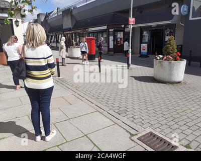 Schlange von Menschen außerhalb zeigen auf Höhe der Beschränkungen warten Zum Kauf von Waren und Einkaufen Covid 19 Coronavirus Soziale Distanzierung Stockfoto
