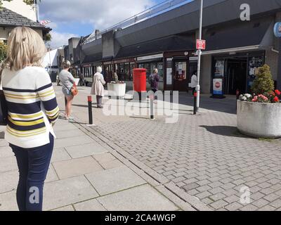 Schlange von Menschen außerhalb zeigen auf Höhe der Beschränkungen warten Zum Kauf von Waren und Einkaufen Covid 19 Coronavirus Soziale Distanzierung Stockfoto