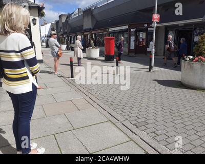 Schlange von Menschen außerhalb zeigen auf Höhe der Beschränkungen warten Zum Kauf von Waren und Einkaufen Covid 19 Coronavirus Soziale Distanzierung Stockfoto