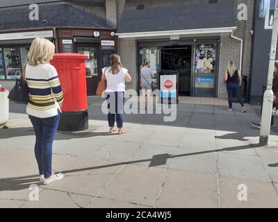 Schlange von Menschen außerhalb zeigen auf Höhe der Beschränkungen warten Zum Kauf von Waren und Einkaufen Covid 19 Coronavirus Soziale Distanzierung Stockfoto