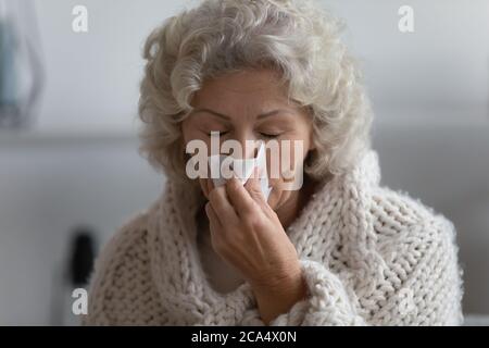 Ältere ungesunde kranke Frau hat Kälte, die ihre laufende Nase bläst Stockfoto